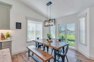 Dining space with an inviting chandelier, vaulted ceiling, and light wood-type flooring