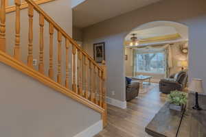 Entrance foyer with hardwood / wood-style floors, a tray ceiling, and ceiling fan