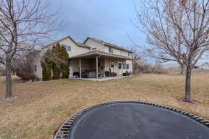 View of front of property with a hot tub, a patio, and a front yard