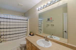 Full bathroom with vanity, a textured ceiling, toilet, and shower / bath combo