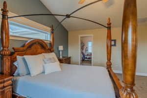 Carpeted bedroom featuring vaulted ceiling and ceiling fan