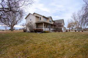 Rear view of house with covered porch and a lawn