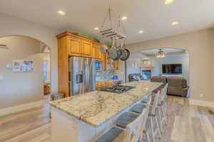 Kitchen with light stone counters, stainless steel appliances, a kitchen bar, and a kitchen island