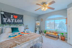 Carpeted bedroom with vaulted ceiling and ceiling fan