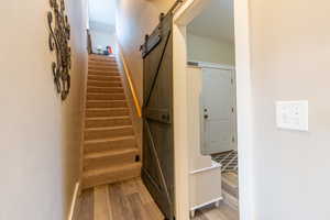 Stairway featuring wood-type flooring and a barn door