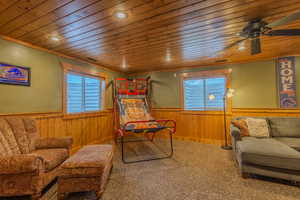 Sitting room with carpet flooring, a wealth of natural light, wood ceiling, and wood walls