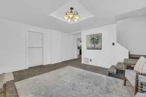 Carpeted living room with a raised ceiling and a notable chandelier