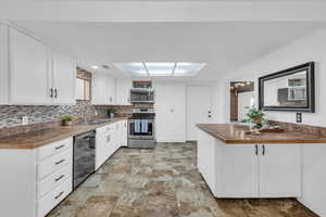 Kitchen featuring stainless steel appliances, white cabinetry, sink, and backsplash