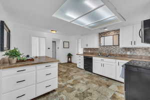 Kitchen with black dishwasher, sink, and white cabinets