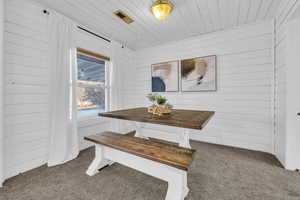 Dining area featuring dark colored carpet, wooden ceiling, wooden walls, and breakfast area