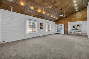 Unfurnished living room featuring french doors, high vaulted ceiling, carpet floors, and wooden ceiling