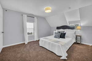 Bedroom with lofted ceiling and dark carpet