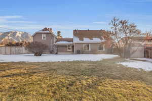 Back of house with central AC and a lawn