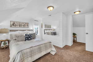 Carpeted bedroom featuring vaulted ceiling and a textured ceiling