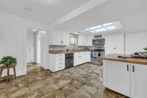 Kitchen featuring sink, butcher block countertops, tasteful backsplash, appliances with stainless steel finishes, and white cabinets