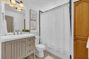 Full bathroom featuring tile patterned floors, toilet, shower / bath combo with shower curtain, and vanity