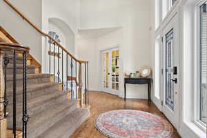 Entrance foyer featuring french doors, a towering ceiling, and hardwood / wood-style floors