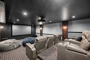 Carpeted home theater room featuring decorative columns and a textured ceiling