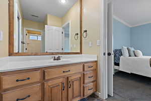 Bathroom featuring vanity, ornamental molding, and a textured ceiling