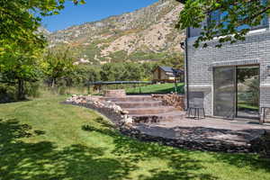 View of green lawn with a mountain view and a patio area