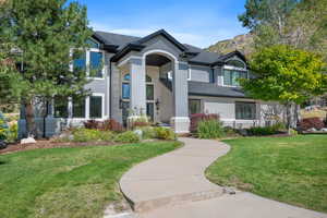 View of front of property with brick siding, a front yard, and roof with shingles
