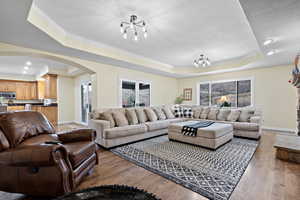 Living room featuring a tray ceiling, plenty of natural light, ornamental molding, and wood-type flooring