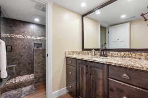 Bathroom with tiled shower, wood-type flooring, and vanity