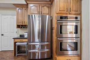 Kitchen with stainless steel appliances, dark hardwood / wood-style flooring, and dark stone counters