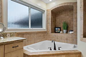 Bathroom with vanity and tiled bath