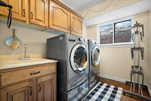 Washroom featuring cabinets, dark hardwood / wood-style floors, washer and clothes dryer, and sink