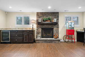 Living room featuring hardwood / wood-style flooring, beverage cooler, and a stone fireplace