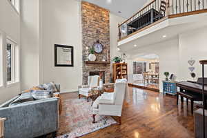 Living room with plenty of natural light, a stone fireplace, and dark hardwood / wood-style flooring