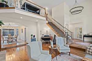 Living room with an inviting chandelier, hardwood / wood-style floors, a towering ceiling, and french doors