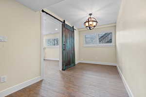 Spare room featuring hardwood / wood-style floors, a chandelier, a barn door, and a textured ceiling