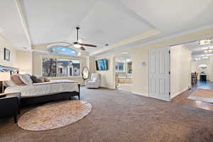 Carpeted bedroom with ceiling fan, ornamental molding, lofted ceiling, and connected bathroom