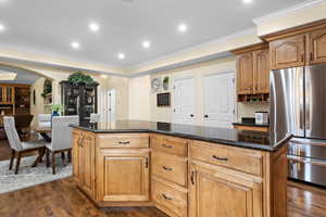 Kitchen featuring dark stone countertops, dark hardwood / wood-style floors, stainless steel refrigerator, and a kitchen island