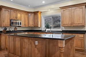 Kitchen with dark stone countertops, a kitchen island, dark hardwood / wood-style floors, and appliances with stainless steel finishes