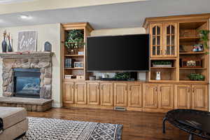 Living room featuring a stone fireplace, dark wood-type flooring, and a textured ceiling