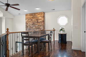 Dining space with vaulted ceiling, dark hardwood / wood-style floors, and ceiling fan