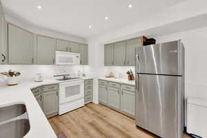 Kitchen featuring white appliances, sink, and light hardwood / wood-style flooring