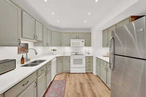 Kitchen featuring sink, white appliances, and light hardwood / wood-style flooring