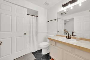 Bathroom featuring vanity, walk in shower, tile patterned floors, and toilet