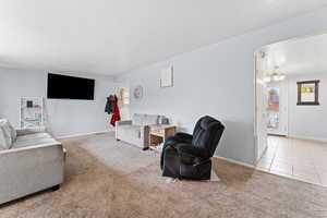 Carpeted living room featuring a textured ceiling and a chandelier