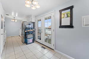 Kitchen featuring an inviting chandelier, light tile patterned flooring, french doors, and white cabinets