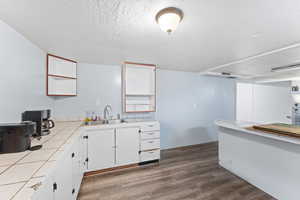 Kitchen with sink, tile countertops, a textured ceiling, dark hardwood / wood-style floors, and white cabinets