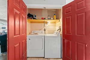 Laundry room with washing machine and dryer and light tile patterned floors