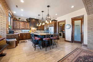 Kitchen with pendant lighting, a center island, a kitchen bar, stainless steel fridge with ice dispenser, and washer / dryer