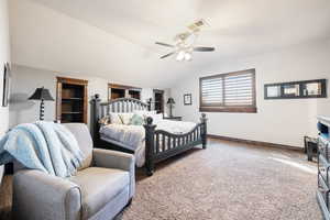 Carpeted bedroom with vaulted ceiling and ceiling fan