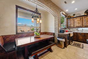 Kitchen featuring breakfast area, tasteful backsplash, light stone counters, and hanging light fixtures