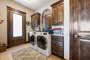 Clothes washing area featuring cabinets and washer and clothes dryer